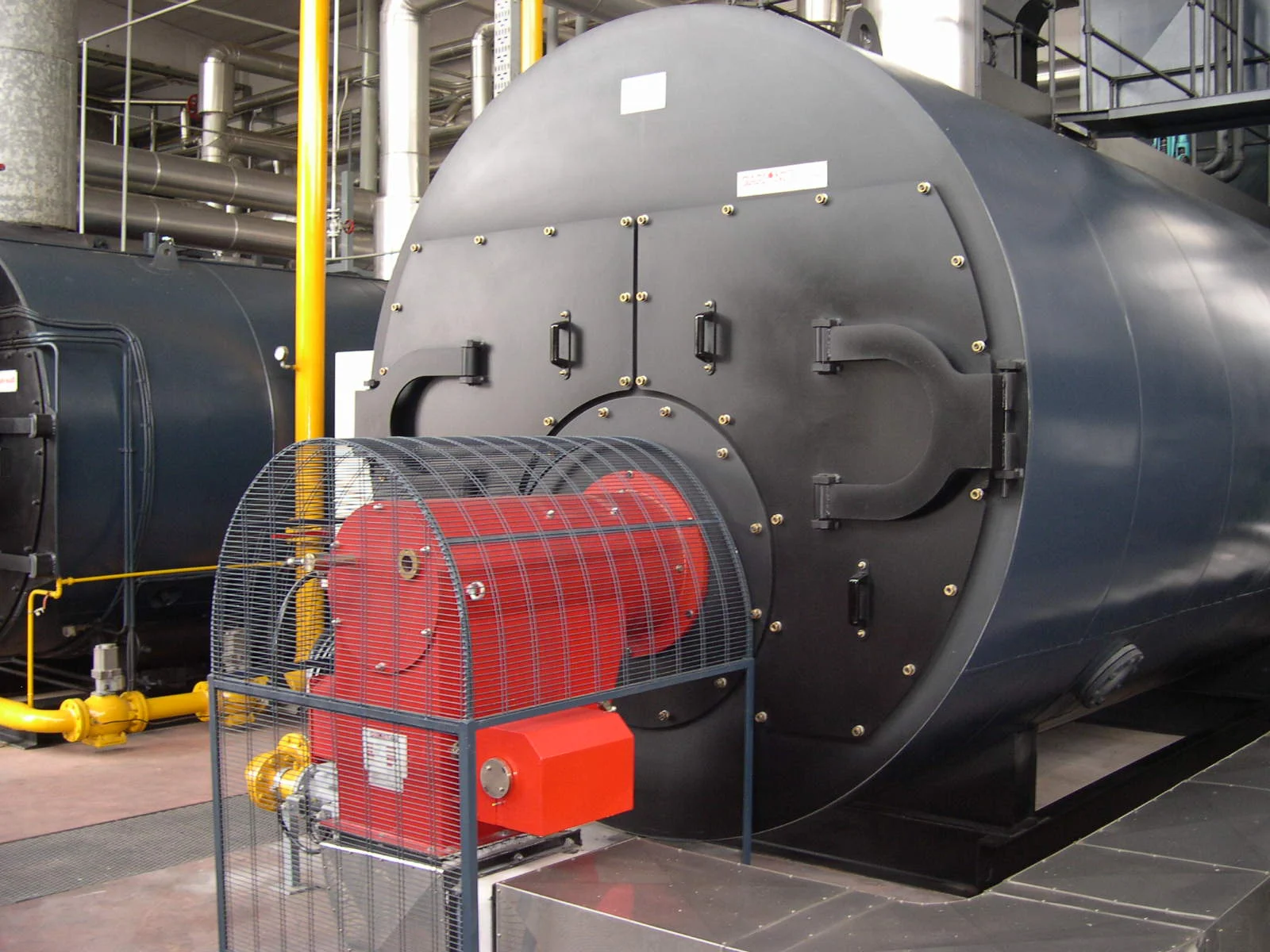 Caldeira a vapor industrial de grande porte com queimador acoplado em planta de produção